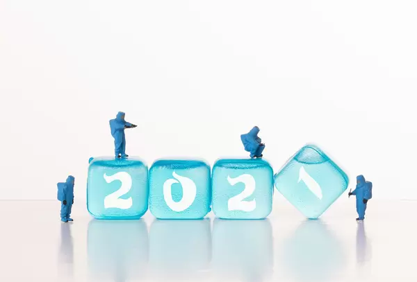 Workers in chemical protection clothes with ice cubes with 2021 text