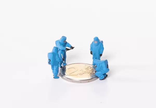 Workes in blue protective suits standing around 2 Euro coin