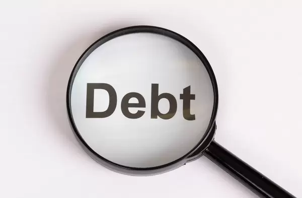 Wort Debt unter einer Lupe mit weißem Hintergrund