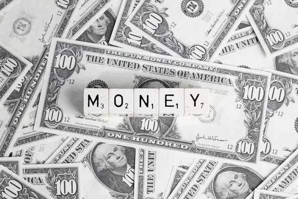 Wort MONEY (Geld) gebildet aus Würfel auf Hintergrund aus US-Dollar Banknoten