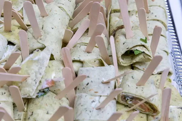 Wraps mit Putenschinken, Salat, Käse und Currygeschmack mit Holzgabelnn an einem Bufet