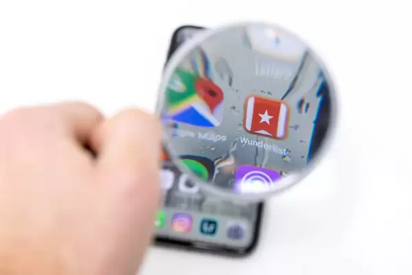 Wunderlist App auf Smartphone durch Lupe betrachtet vor weißem Hintergrund