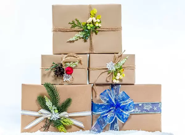 Wundervoll geschmückte gestapelte Weihnachtsgeschenke in Naturpapier im Schnee