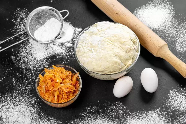 Yeast dough and fried cabbage on the table with flour and eggs (Flip 2019)