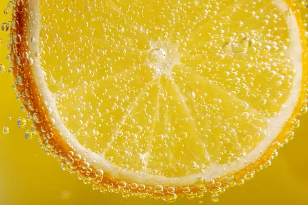 Yellow background with lemon slice with bubbles, close-up