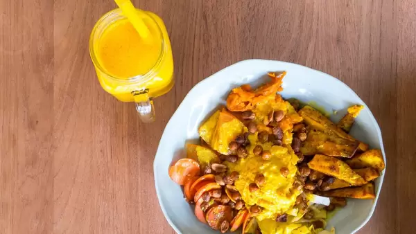 Yellow Bowl mit Safran Bulgur, Süßkartoffel, Pastinaken, gebackene Kichererbsen, Kaki, Sesam-Möhren, geröstete Erdnüsse, Kürbis-Hummus, Kurkuma Tahini-Dressing