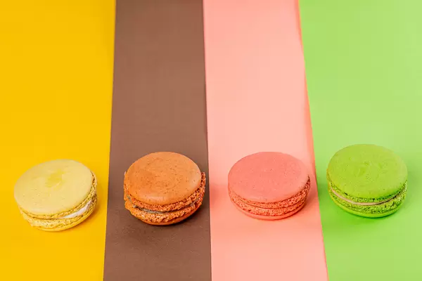 Yellow, brown, pink and green macaroons on multi-colored backgrounds