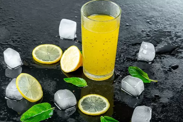 Yellow cocktail with ice cubes and lemon