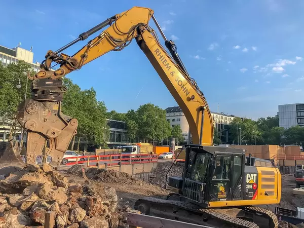 Yellow excavator works on a construction site for the new office tower "Wallarkaden" next to U-Rudolfplatz and Hahnentor in Cologne