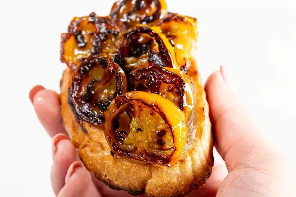 Yellow grilled tomatoes on toasted bread in a woman's hand (Flip 2019)