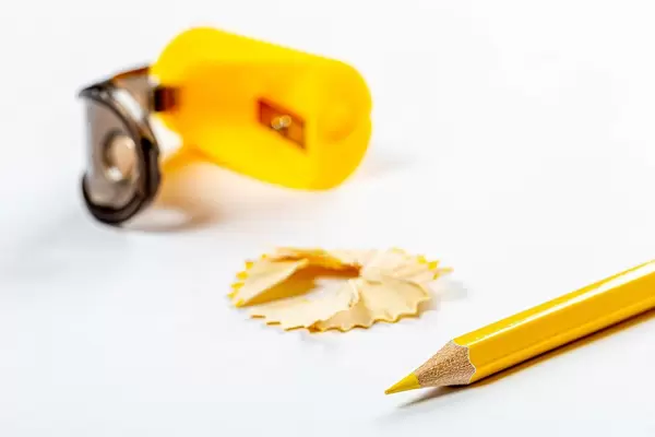 Yellow pencil, sawdust and pencil sharpener on white background (Flip 2019)