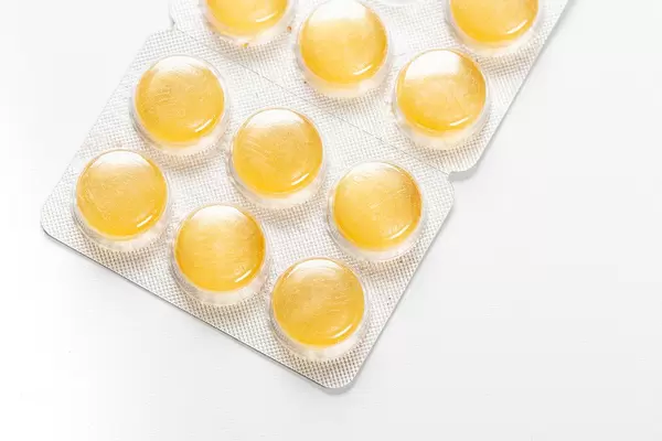 Yellow pills-lollipops in a blister on a white background