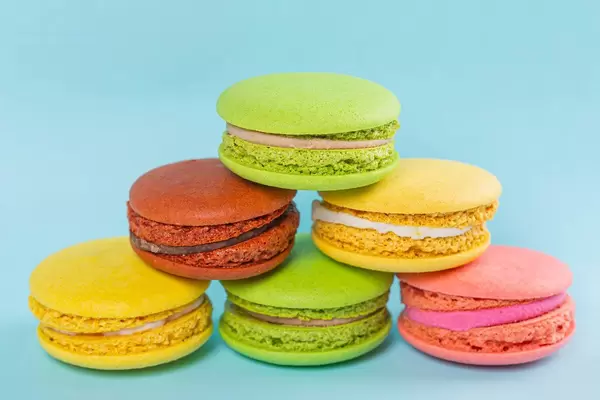 Yellow, pink, green and brown macaroon cookies on a blue background