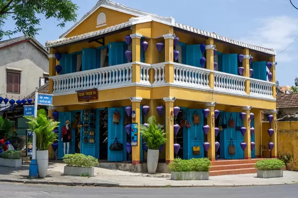 Yellow Shop with Blue Wooden Doors selling Leather Shoes and Bags with Blue Lanterns for Decoration in Hoi An, Vietnam