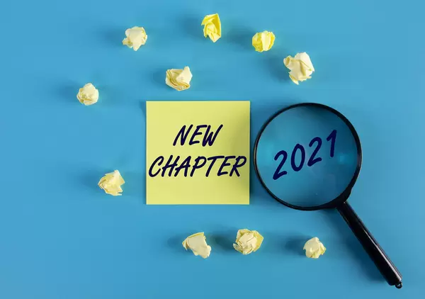 Yellow sticky note and magnifying glass with 2021 New Chapter text