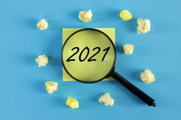 Yellow sticky note and magnifying glass with 2021 text