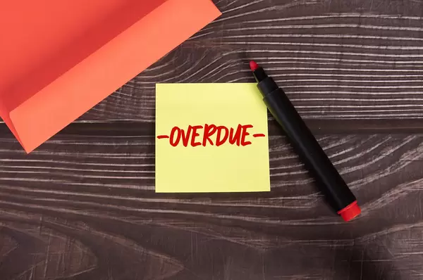 Yellow sticky note with Overdue text on wooden table