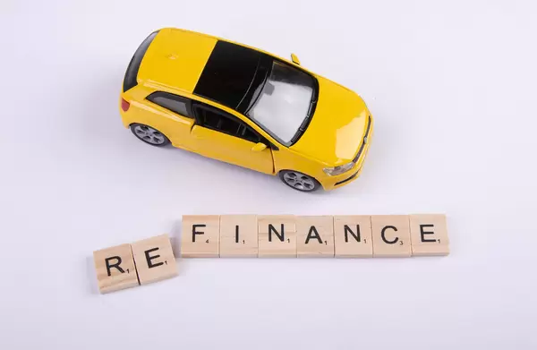Yellow toy car with Refinance text on wooden blocks