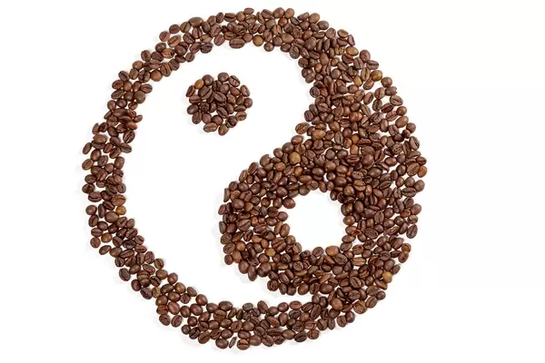 Yin and yang symbol made of coffee beans on white