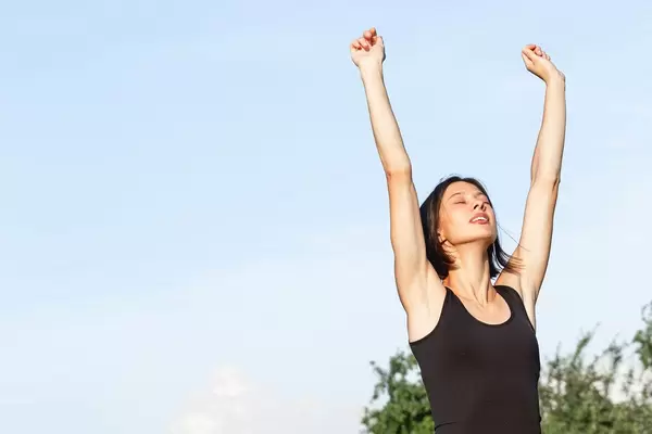 Yoga pose Urdhva Hastasana, girl stretching arms up in a standing position against the sky