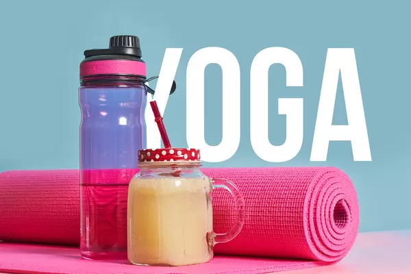 Yoga supplies - yoga mat, a bottle of water and fresh smoothie over blue background