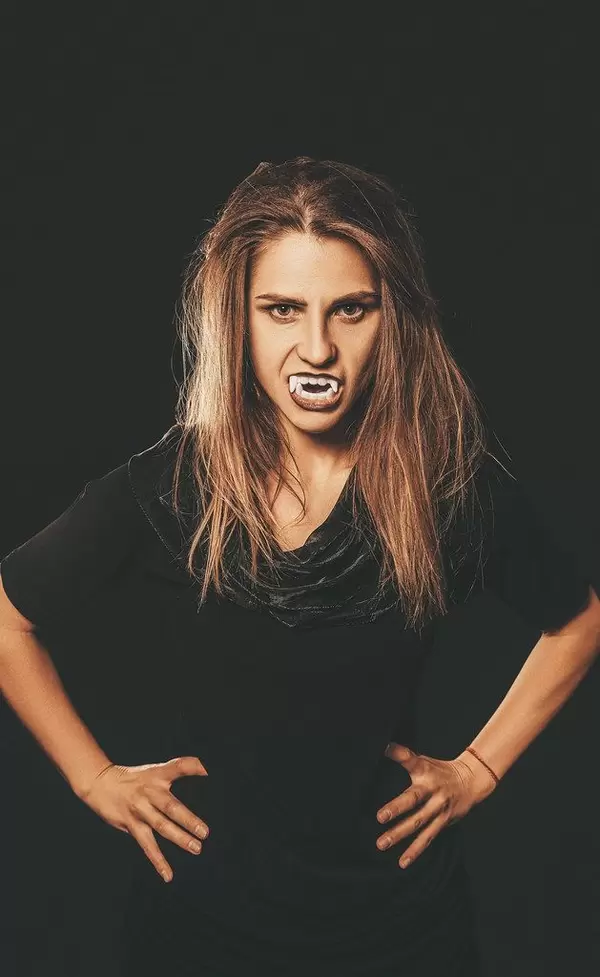 Young beautiful furious woman with vampire fangs