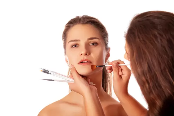 Young beautiful woman applying makeup by makeup artist