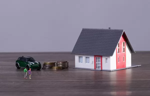 Young couple with house, car and coin stacks