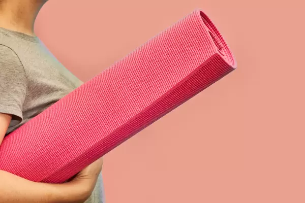 Young female holding yoga mat