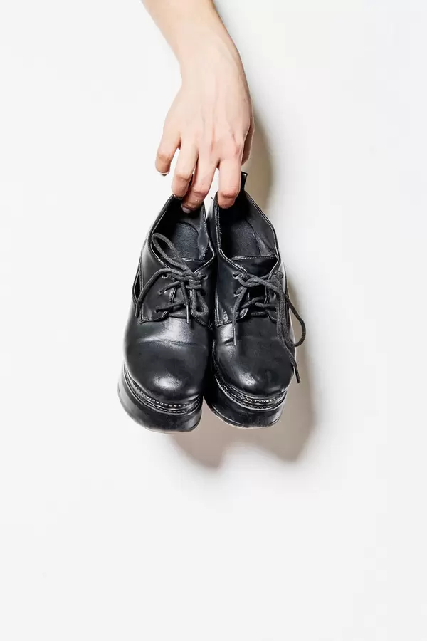 Young female holds leather boots on platform