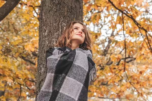 Young girl in a plaid posing near a tree