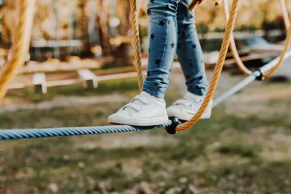 Young girl walking on rope in rope park. Legs detail