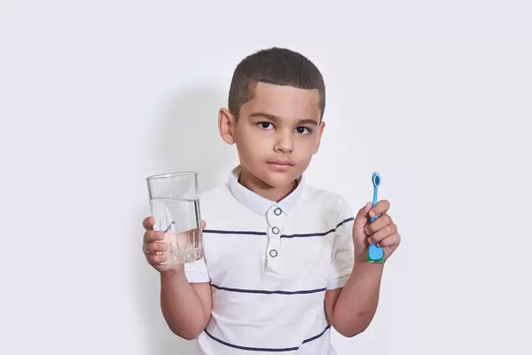 Young kid hold a toothbrush and a glass of water