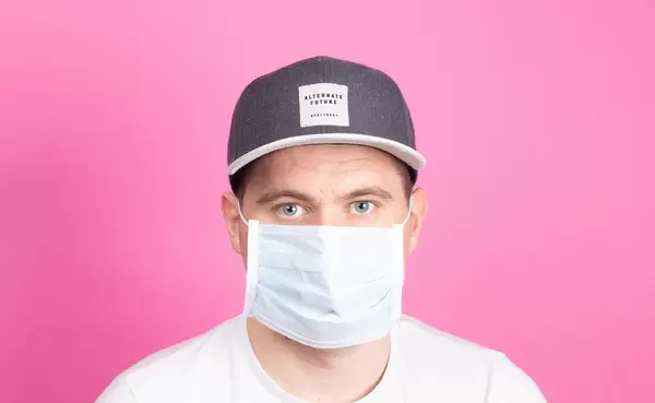 Young man with medical flu mask on pink background