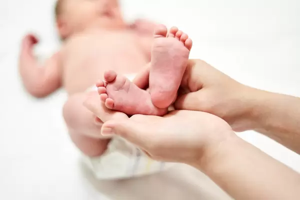 Young mother holds baby feet