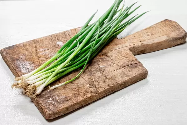 Young onions on an old wooden kitchen Board (Flip 2019)