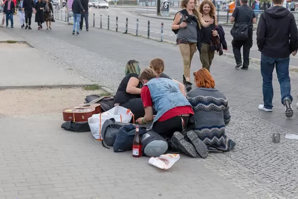Young people with guitar sittting on the pavement