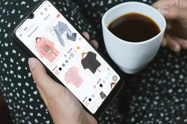 Young woman choosing clothes in online shop application