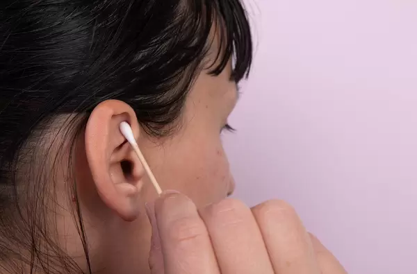 Young woman cleaning her ears with cotton sticks