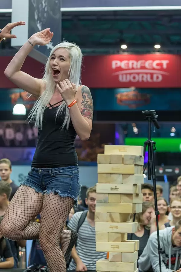 Young woman high fives after winning at Jenga tower game at Gamescom 2018