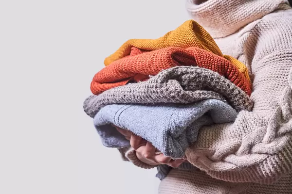 Young woman holding knitted woolen pullovers