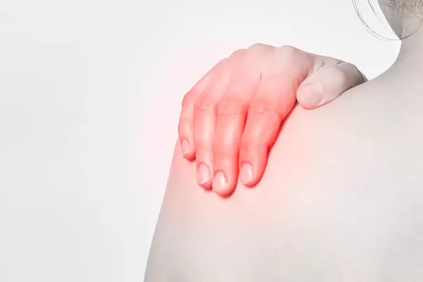 Young woman suffering from pain in shoulder