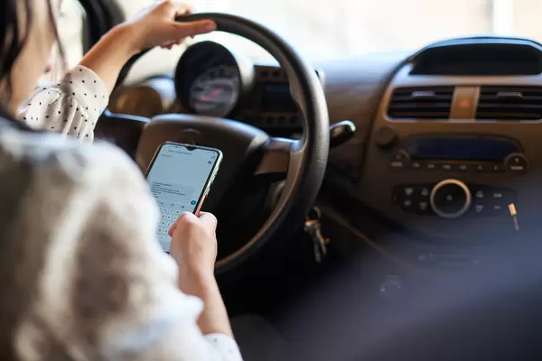 Young woman texting while driving car