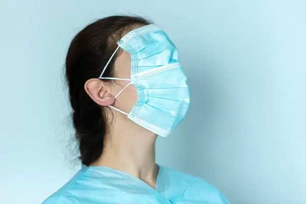 Young woman wearing two medical face mask over her eyes, nose and mouth