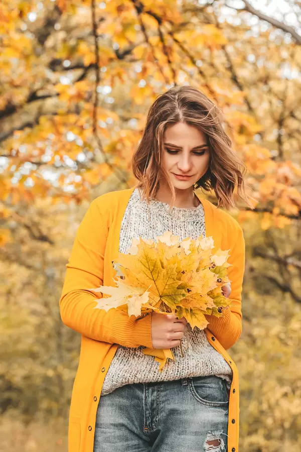 Young woman with autumn leaves in hand