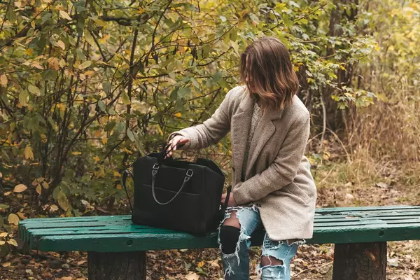 Young woman with black bag on a bench in the park