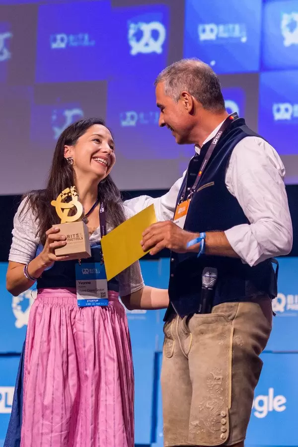 Yvonne Rusche von Münchner Startup Hawa Dawa, das sich dem Thema Luftqualität widmet, bekommt die #bits19 goldene Brezel und bedankt sich bei Andreas Etten von 10x