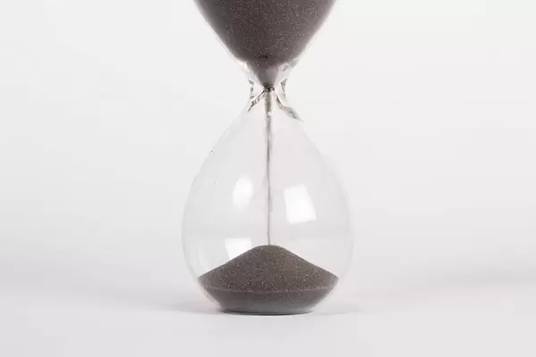 Zeit und Vergänglichkeit – laufende Sanduhr vor weißem Hintergrund