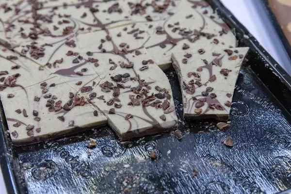Zerbrochene Tafel Vanilleschokolade mit Schokoladenraspeln, auf einem schwarzen Tablett
