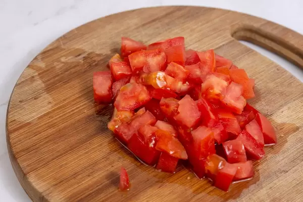 Zerkleinerte Tomaten auf einem runden Holzschneidebrett